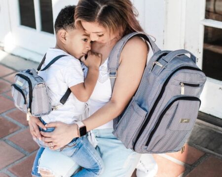 mom holding a toddler while wearing a diaper bag