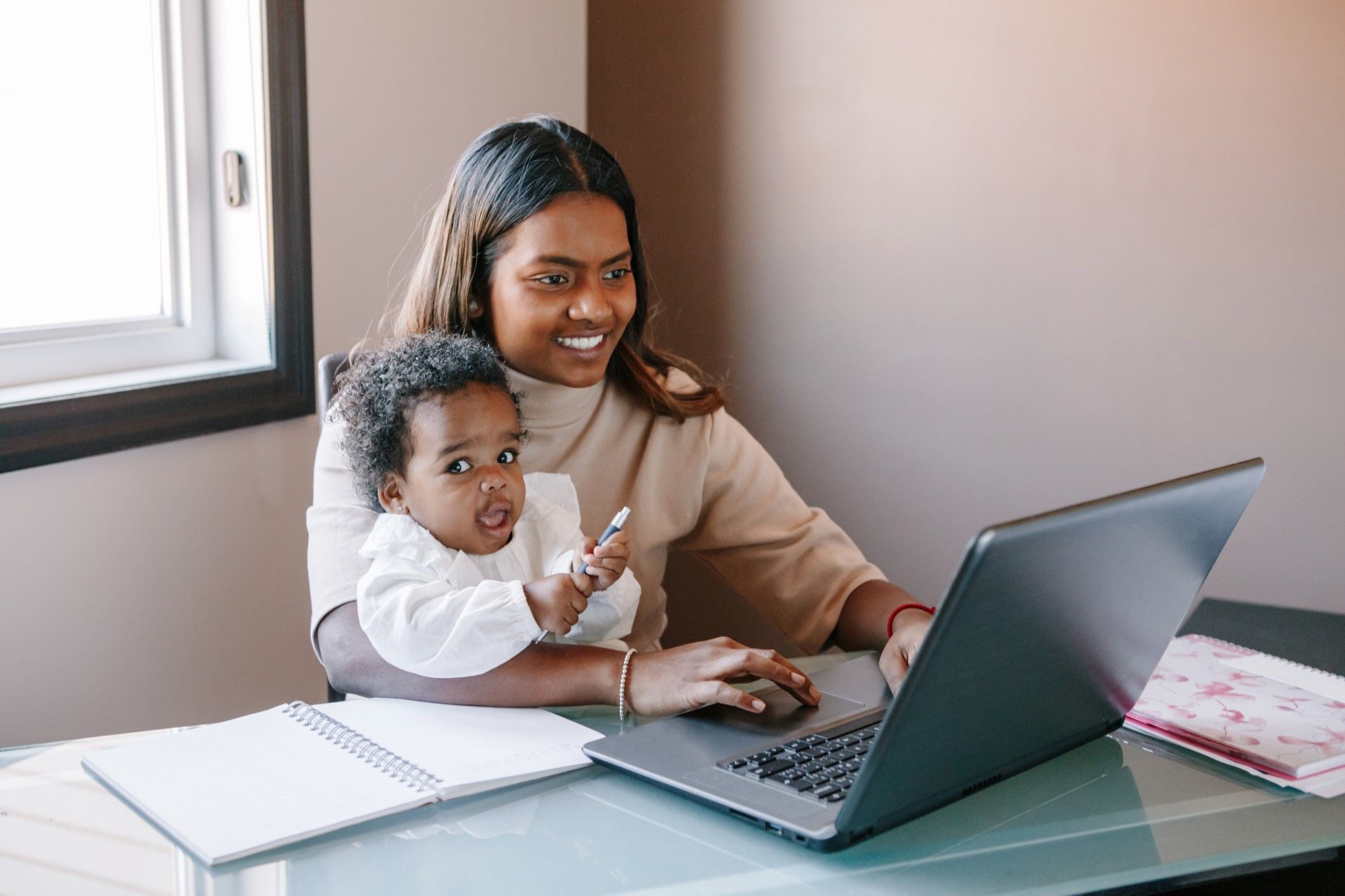 mom working on a laptop with toddler in her lap