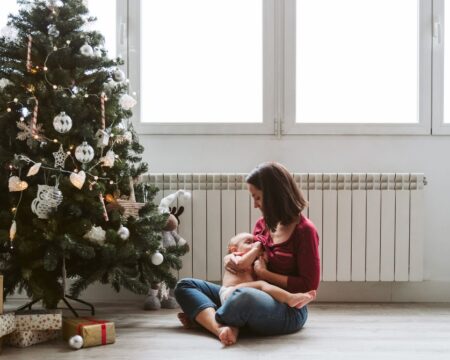 mother breastfeeding baby by christmas tree
