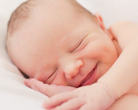 newborn baby smiling in his sleep with hand under head italian baby names