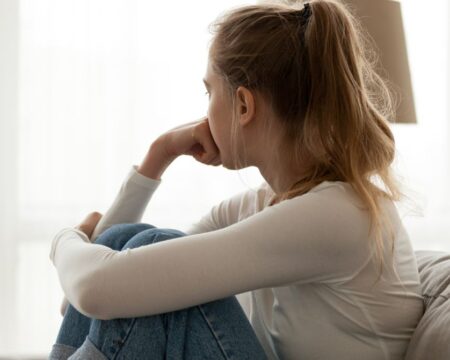 sad teen at home on couch looking away