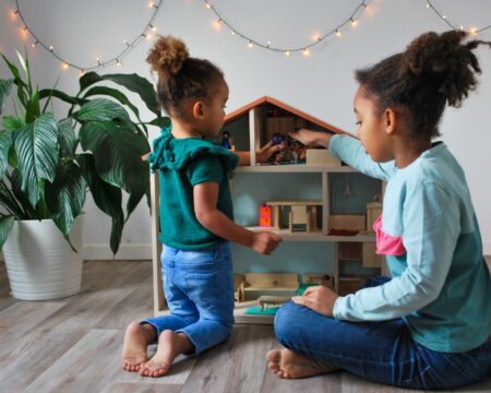 two girls playing with a dollhouse