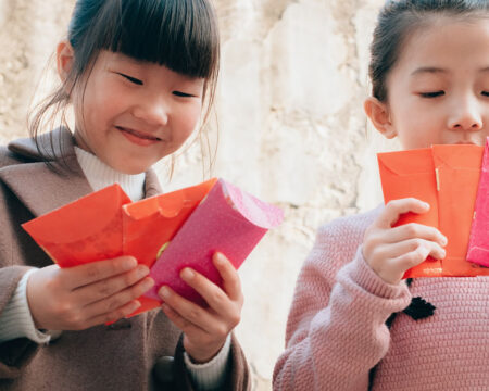 two young girls holding red envelopes for the lunar new year