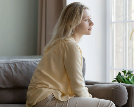 woman dealing with infertility looking out the window looking solemn