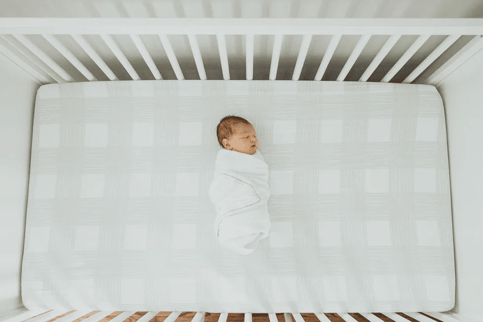 baby sleeping in swaddle in crib to reduce sids risk